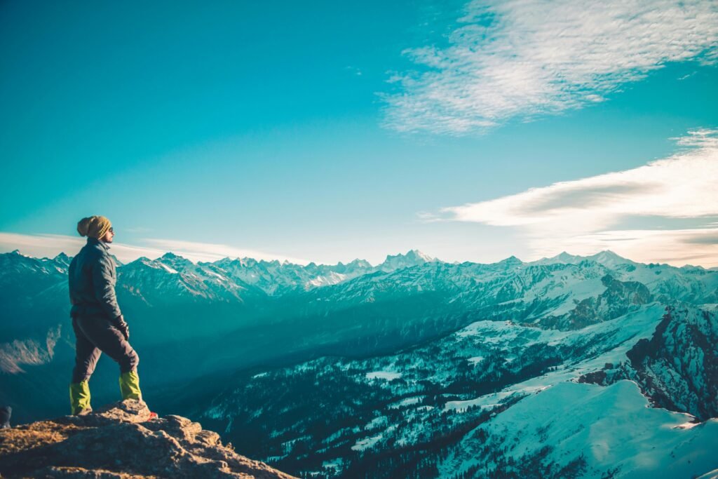 Landscape: "A panoramic view of the snow-capped Himalayan mountains surrounding the town of Manali, with lush green valleys and a clear blue sky." Local Culture: "A traditional Himachali woman in colorful attire standing beside a wooden house with intricate carvings, set against the backdrop of the Manali mountains." Adventure Activities: "Tourists enjoying paragliding over the verdant hills and scenic landscapes of Manali, with the Himalayan range in the distance." Manali's Streets: "A bustling street in Manali filled with shops selling local handicrafts, with a backdrop of picturesque mountains and pine trees." Nature: "The serene Beas River flowing through the valley of Manali, surrounded by tall pine trees and rugged mountain terrain."